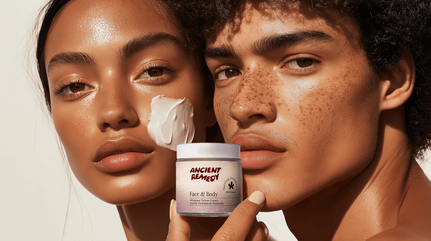 Model applying tallow moisturizer from Ancient Remedy on her face while holding the product jar in a sunlit setting.