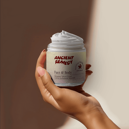 Hand holding a jar of Ancient Remedy Tallow Moisturizer Face & Body Moisturizer, featuring a creamy texture for hydration.